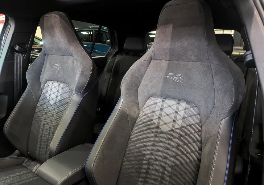 Gros plan sur les sièges avant en tissu gris et alcantara avec logo R, intérieur d'une Volkswagen Golf 2025.