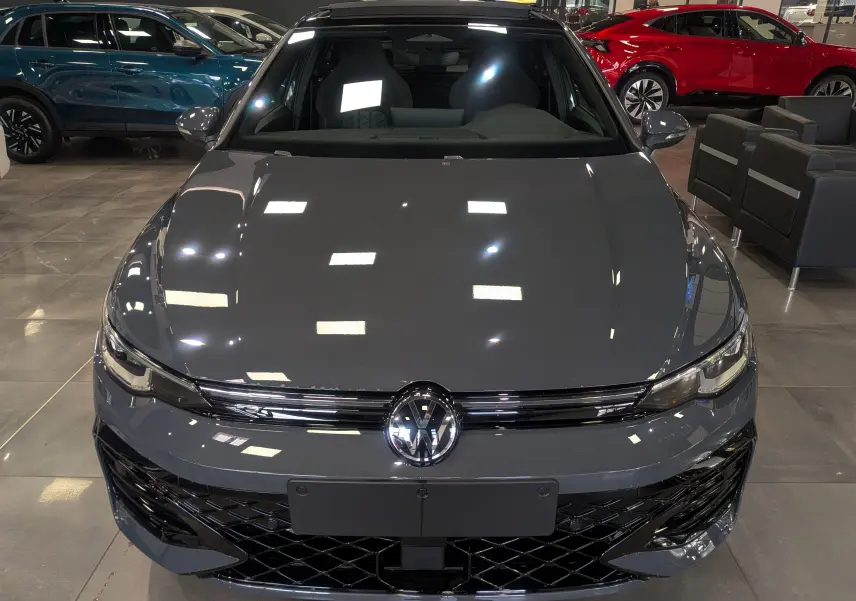 Vue frontale d'une Volkswagen Golf 1.5 eTSI R-Line Limited en gris dauphin, avec calandre noire et logo VW brillant.