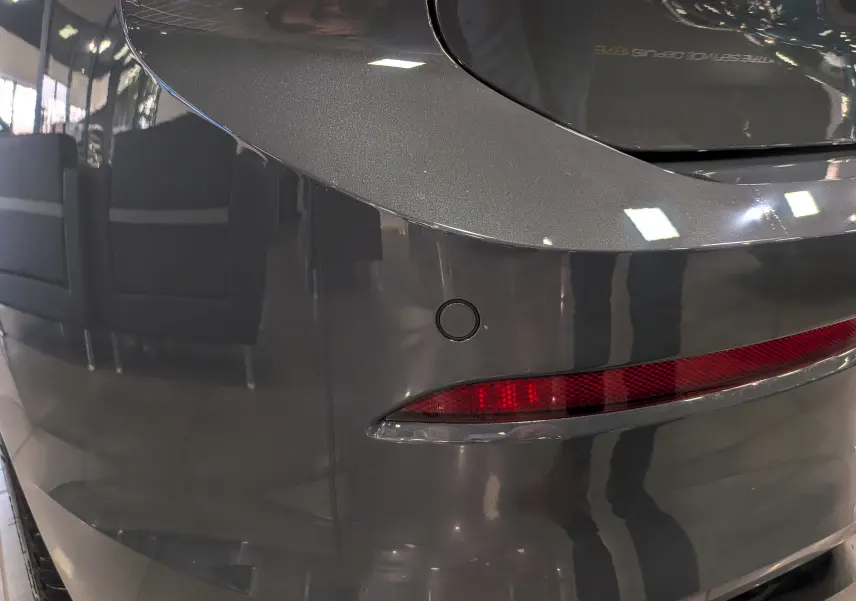 Gros plan sur le pare-chocs arrière gris dauphin d'une Volkswagen Golf 1.5 eTSI 2025 avec feu arrière et capteur de recul.