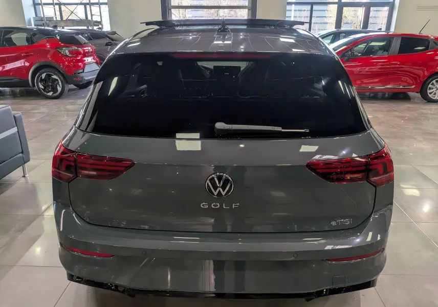 Vue arrière d'une Volkswagen Golf 1.5 eTSI 150 CH R-Line Limited gris dauphin dans un showroom lumineux.