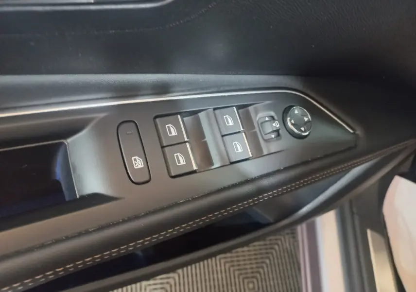 Vue rapprochée des commandes des vitres et rétroviseurs sur la porte côté gauche d’un Peugeot 3008 gris clair.
