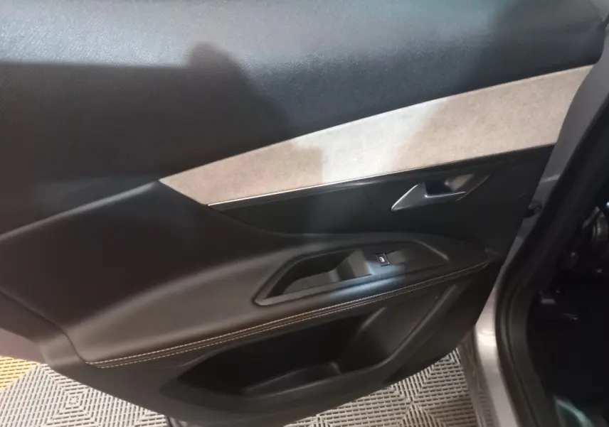 Vue intérieure côté gauche de la porte arrière grise du Peugeot 3008 2022 avec garniture noire et beige et commande de vitre.