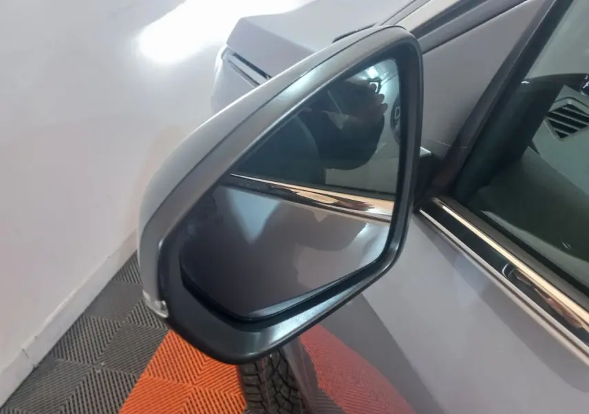 Rétroviseur côté gauche d’un Peugeot 3008 gris clair, vue rapprochée avec reflet et détails de la portière.