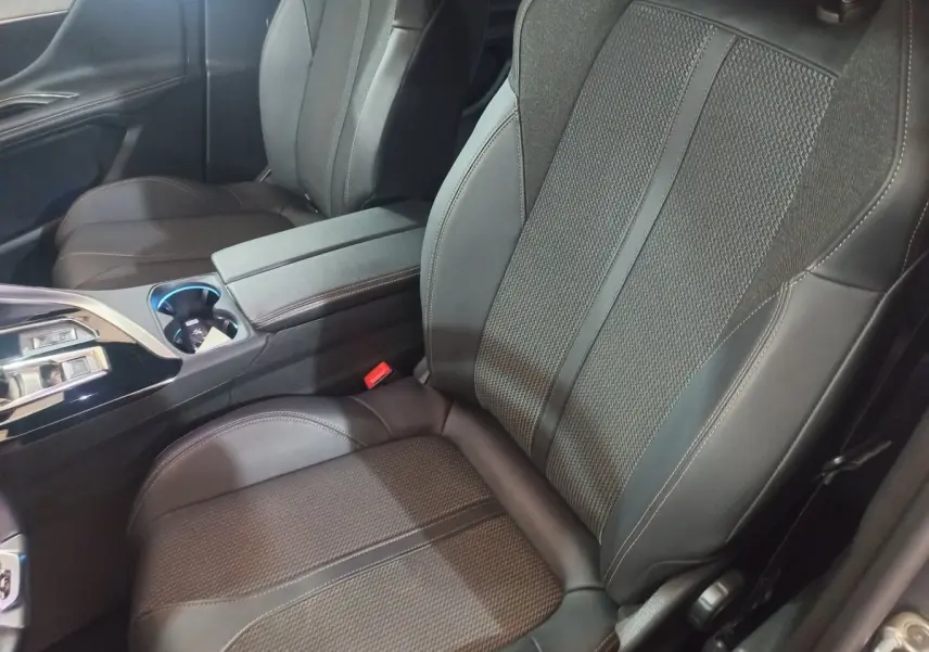 Vue rapprochée des sièges avant en cuir noir du Peugeot 3008 GT 2022, avec console centrale et accoudoir.