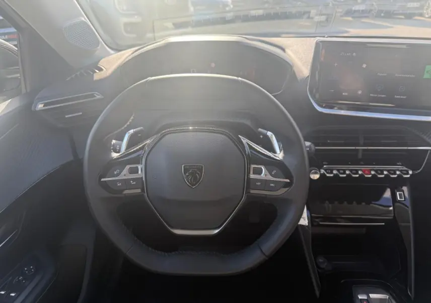 Vue intérieure centrée sur le volant compact de la Peugeot 208 Hybrid 110 e-DCS6 Allure avec tableau de bord numérique et écran tactile.