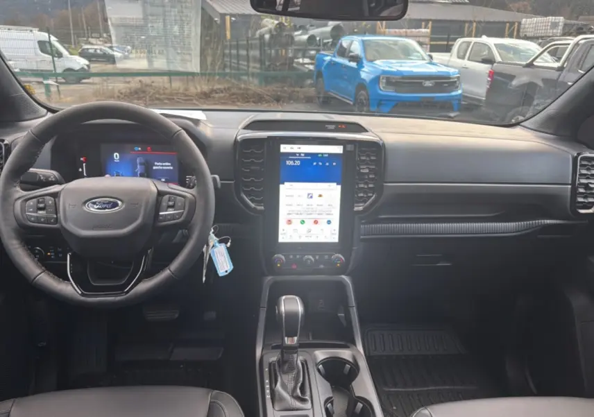 Vue intérieure avant du Ford Ranger 2026 avec tableau de bord noir et écran tactile vertical lumineux.