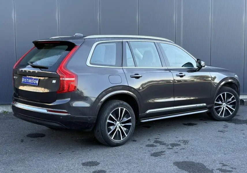 Volvo XC90 T8 hybride gris Platinium vu de 3/4 arrière droit avec jantes alliage noires et chrome aux vitres.
