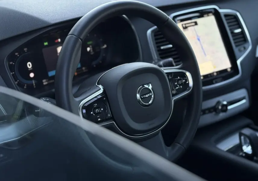 Vue rapprochée du volant et du tableau de bord digital du Volvo XC90 T8 hybride avec écran tactile central.