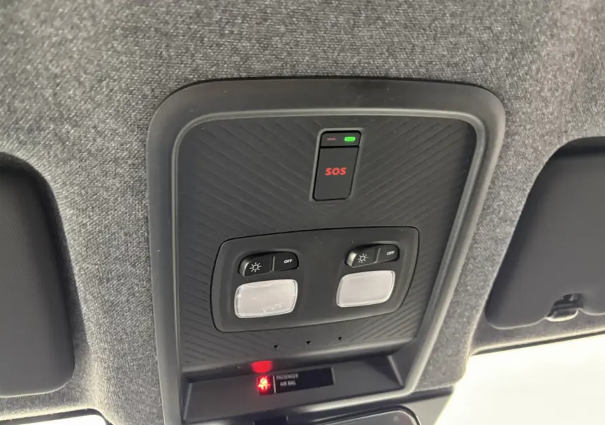 Vue en gros plan du plafonnier gris avec bouton SOS et commandes d'éclairage du Dacia Duster noir 2025 hybride.