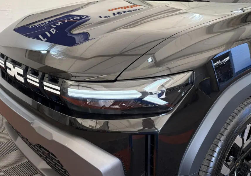 Gros plan sur l'avant droit noir du Dacia Duster 2025 avec phares LED et calandre distinctive.
