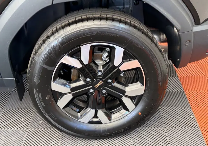 Gros plan sur la roue avant droite du Dacia Duster noir 2025 avec jante alliage bicolore et pneu Hankook