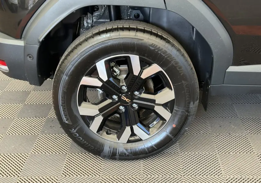 Gros plan sur la roue arrière droite du Dacia Duster noir 2025 avec jante alliage bicolore et pneu Hankook.