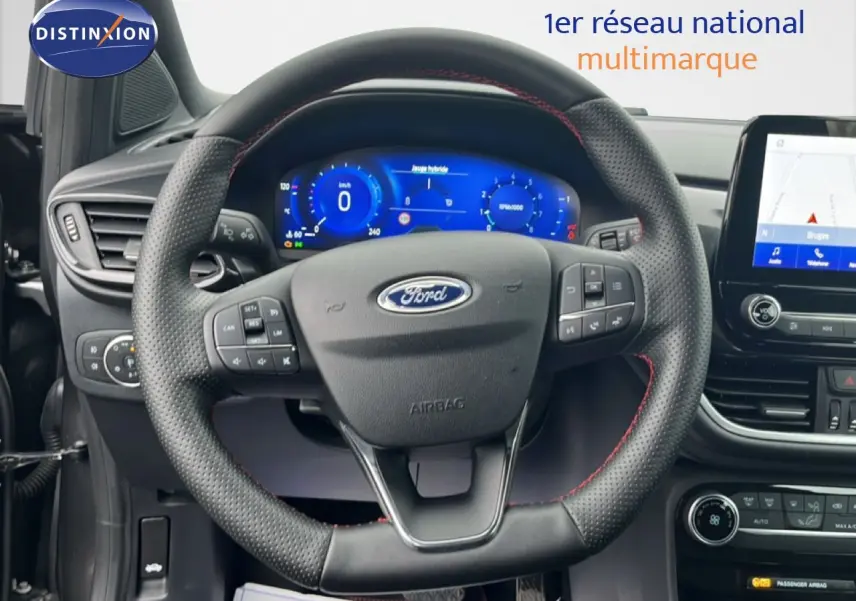 Vue rapprochée du volant perforé avec surpiqûres rouges et tableau de bord numérique du Ford Puma gris magnétique 2024.