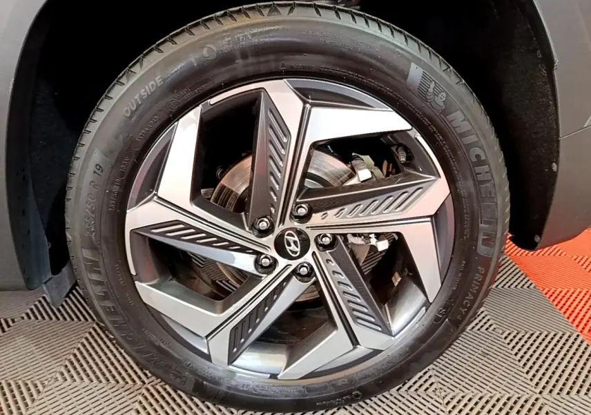 Gros plan sur la roue avant droite du Hyundai Tucson gris foncé, jante alliage au design moderne et pneu Michelin.