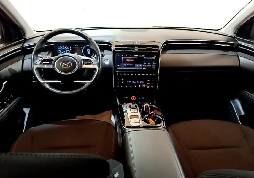 Vue intérieure avant du Hyundai Tucson 2022, tableau de bord noir avec écran tactile central et volant multifonctions.