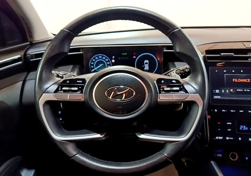 Vue intérieure centrée sur le volant cuir noir du Hyundai Tucson 2022 avec tableau de bord digital et écran tactile.