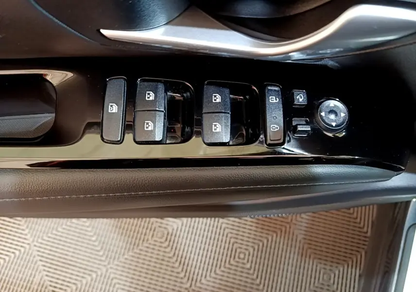 Gros plan sur les commandes de lève-vitres et rétroviseurs côté conducteur du Hyundai Tucson gris foncé, intérieur noir.