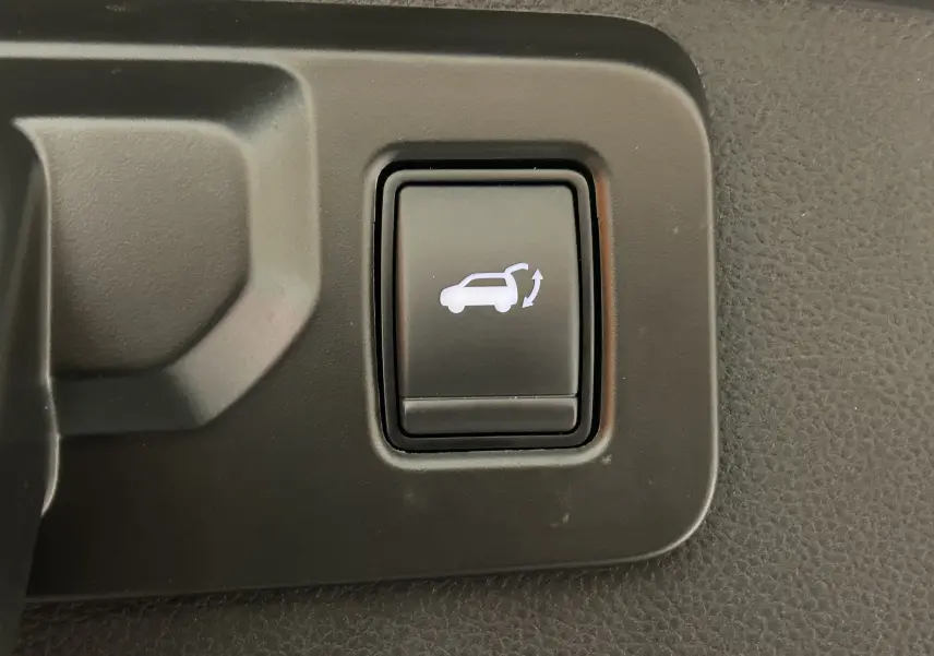 Bouton intérieur noir avec symbole blanc d'ouverture de hayon sur Renault Austral E-Tech blanc nacré.