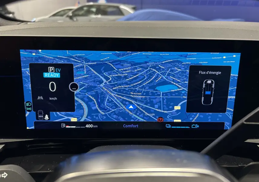 Vue intérieure du tableau de bord numérique du Renault Austral blanc nacré, affichant la navigation GPS et le flux d'énergie hybride.