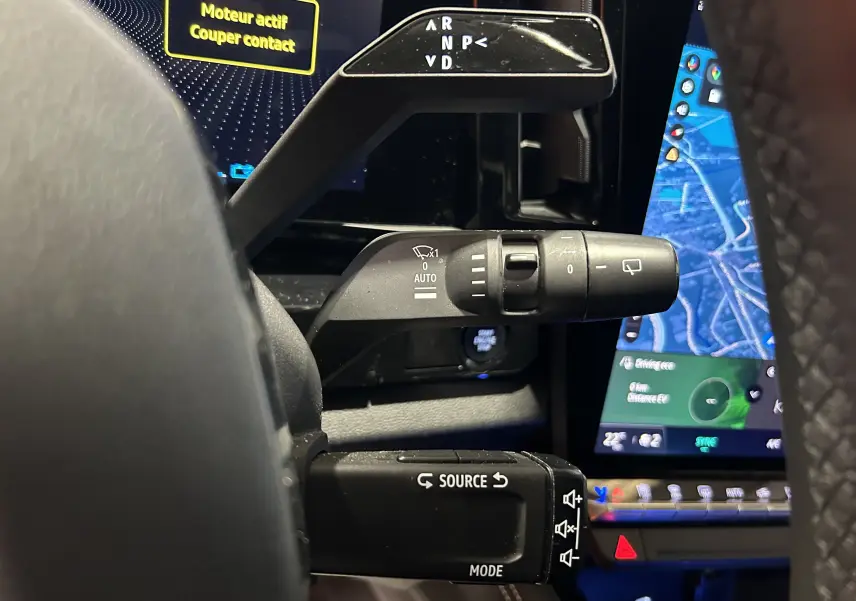 Gros plan sur les commandes au volant du Renault Austral blanc nacré, avec écran tactile et affichage numérique en arrière-plan.