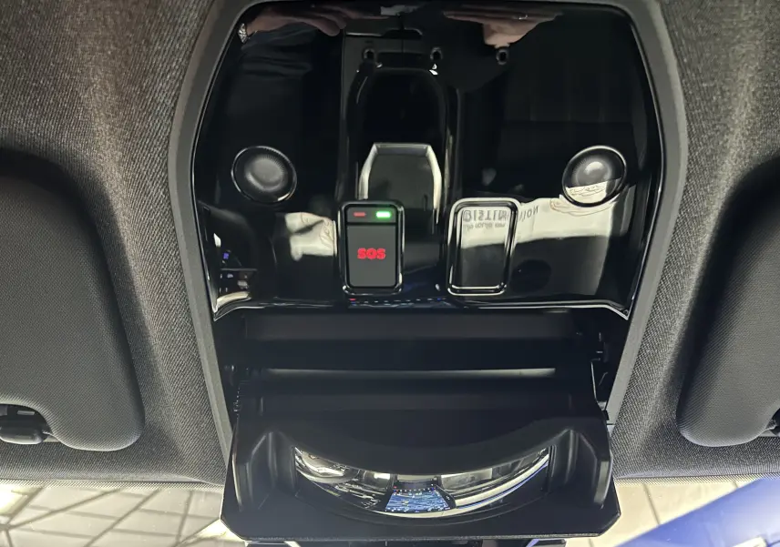 Vue intérieure du plafonnier noir brillant avec bouton SOS rouge et compartiment ouvert dans un Renault Austral blanc nacré.