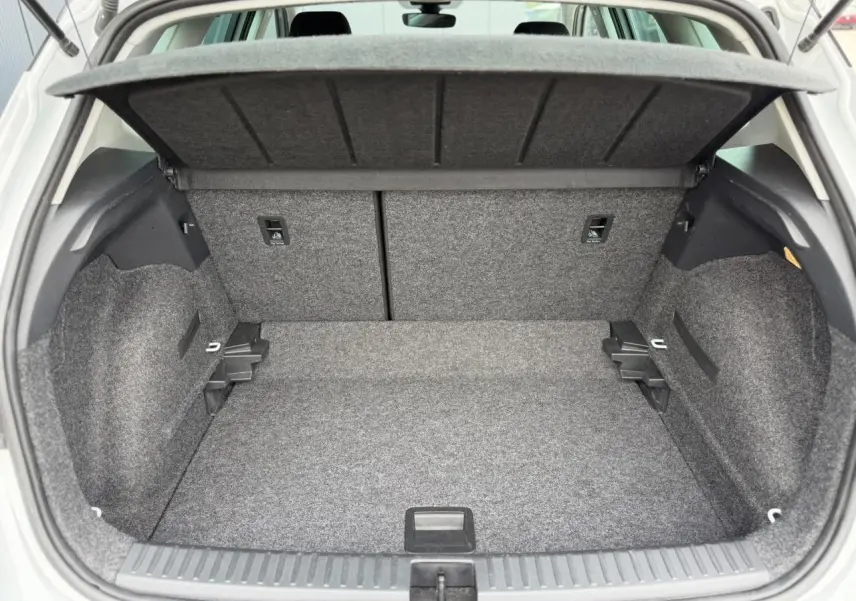 Coffre ouvert vu de l'arrière d'un SEAT Arona blanc, montrant un espace de rangement propre et bien agencé.