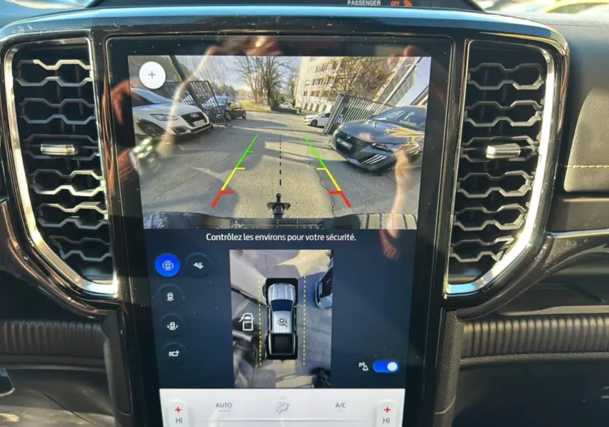 Vue intérieure du tableau de bord du Ford Ranger 2025 avec écran tactile affichant la caméra de recul et l'aide au stationnement.
