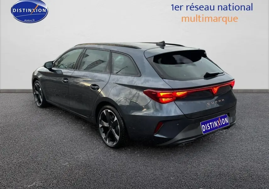 Vue 3/4 arrière droite d'une CUPRA Leon ST gris magnétique avec feux arrière LED allumés et jantes alu distinctives.