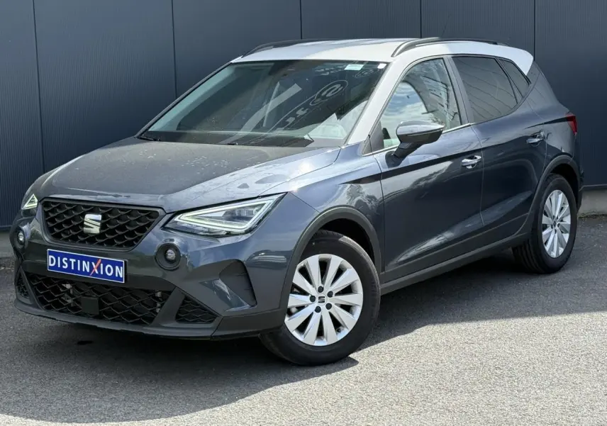 SEAT Arona TSI 115 Style 2025 en 3/4 avant droit, gris magnétique avec toit blanc contrasté et jantes alliage.