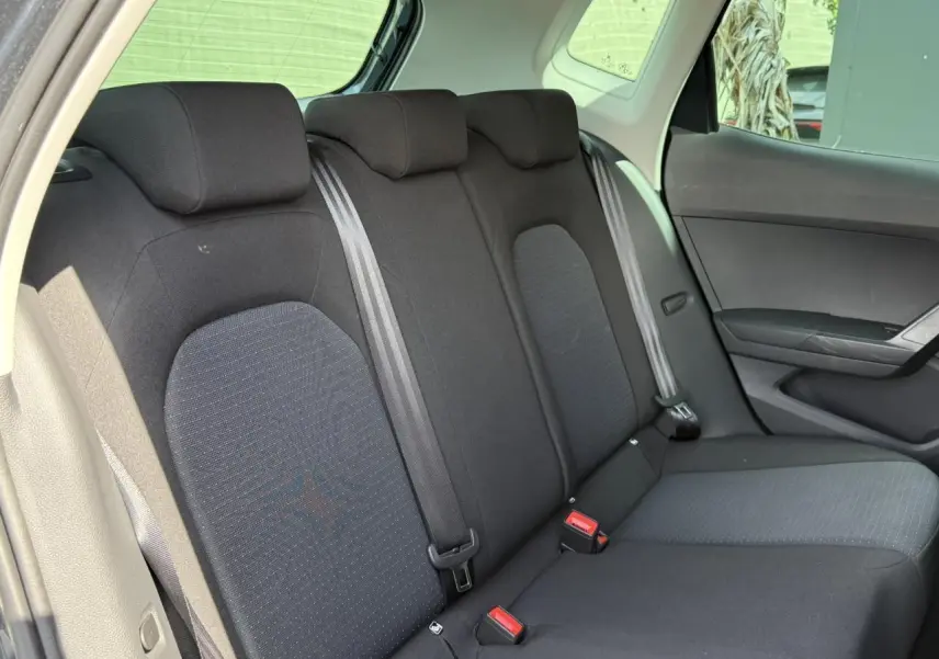 Vue intérieure côté droit montrant la banquette arrière noire du SEAT Arona TSI 115 Style 2025 avec ceintures grises.