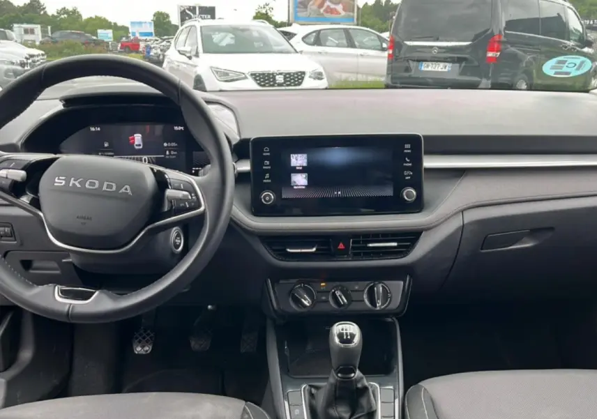 Vue intérieure frontale du tableau de bord et volant noir d'une Skoda Fabia 2025 avec écran tactile et levier de vitesse manuel.