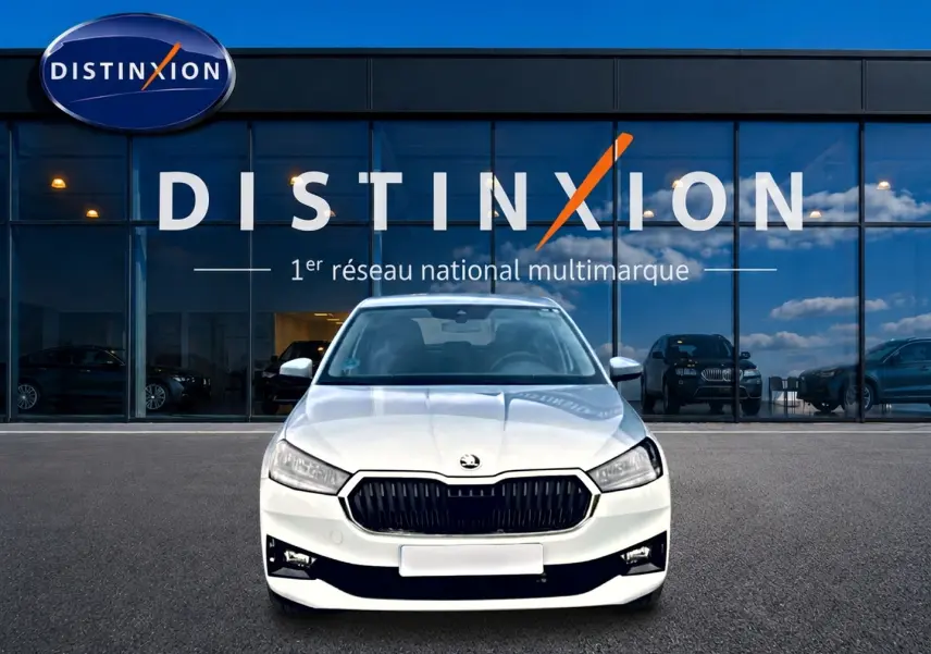 Vue avant d'une Skoda Fabia blanche 2025 avec calandre noire et phares LED devant une vitrine Distinxion.