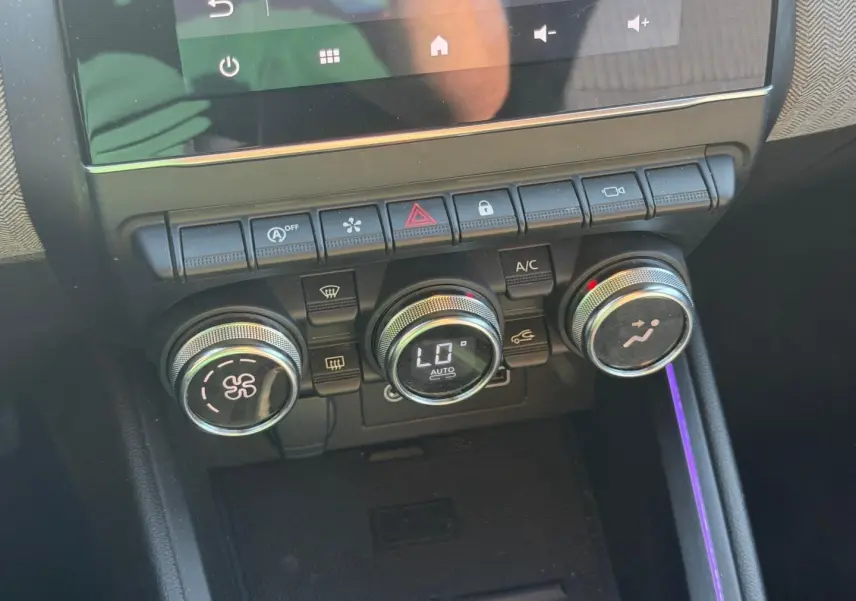 Gros plan sur les commandes de climatisation avec éclairage d’ambiance violet dans l’habitacle d’une Renault Clio 2025.