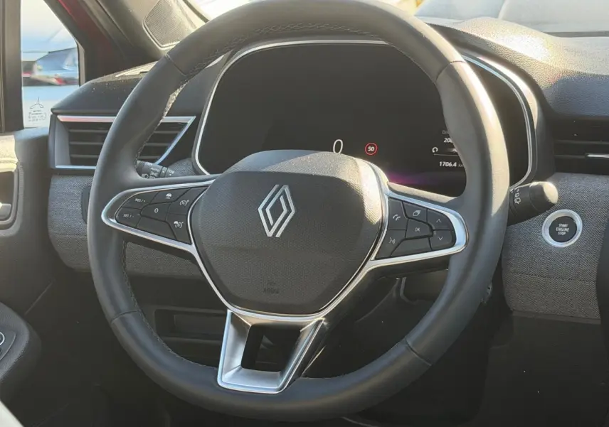 Vue rapprochée du volant multifonction noir de la Renault Clio 2025 avec bouton start/stop et tableau de bord numérique.