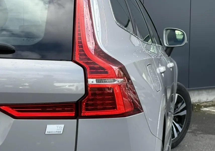 Vue 3/4 arrière droit du Volvo XC60 T6 AWD PHEV gris silver avec feux arrière LED et badge Recharge visible.