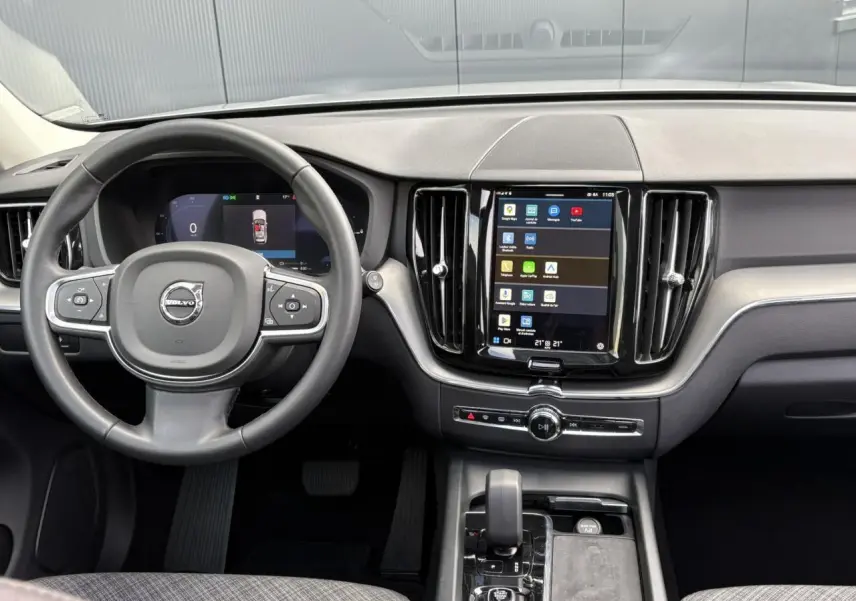 Intérieur du Volvo XC60 T6 AWD PHEV 2024 montrant le tableau de bord noir avec écran tactile vertical et volant simili-cuir.