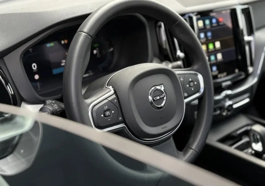 Volant simili-cuir noir avec logo Volvo, tableau de bord digital et écran tactile dans l'habitacle du XC60 2024.