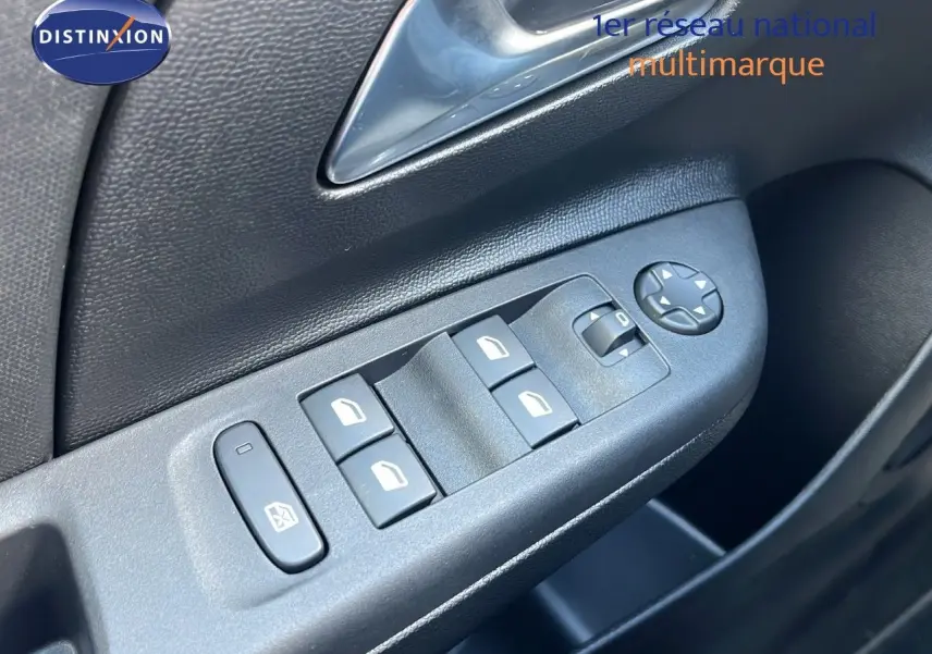 Gros plan sur les commandes des vitres électriques et rétroviseurs côté conducteur d'une Opel Corsa gris Kristal Metal.