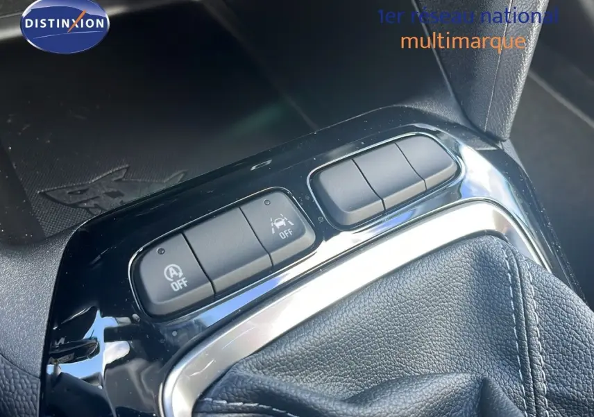 Gros plan sur la console centrale de l'Opel Corsa 2025, montrant les boutons de contrôle et le soufflet de levier de vitesse en cuir noir.