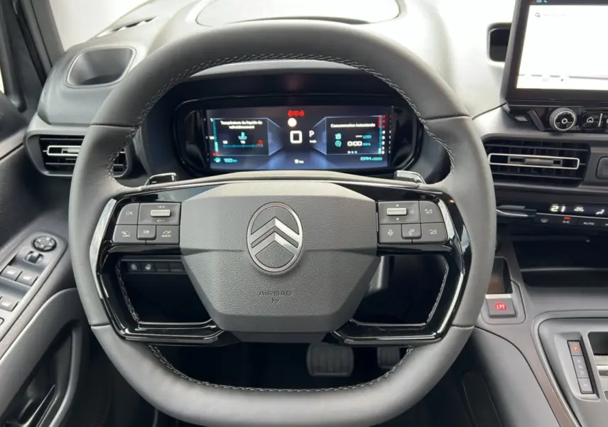 Vue intérieure centrée sur le volant noir du Citroën Berlingo 2025 avec tableau de bord numérique et commandes intégrées.