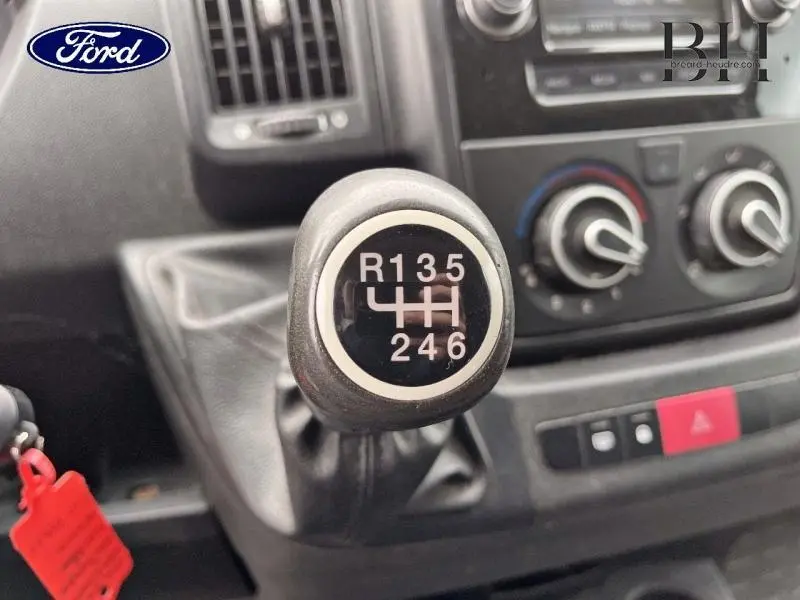 Gros plan sur le levier de vitesses manuel avec schéma 6 rapports dans un intérieur sombre de véhicule utilitaire.