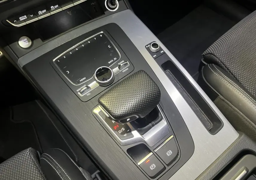 Vue rapprochée de la console centrale grise de l'Audi Q5 S line 2019 avec levier de vitesse et commandes multimédia.