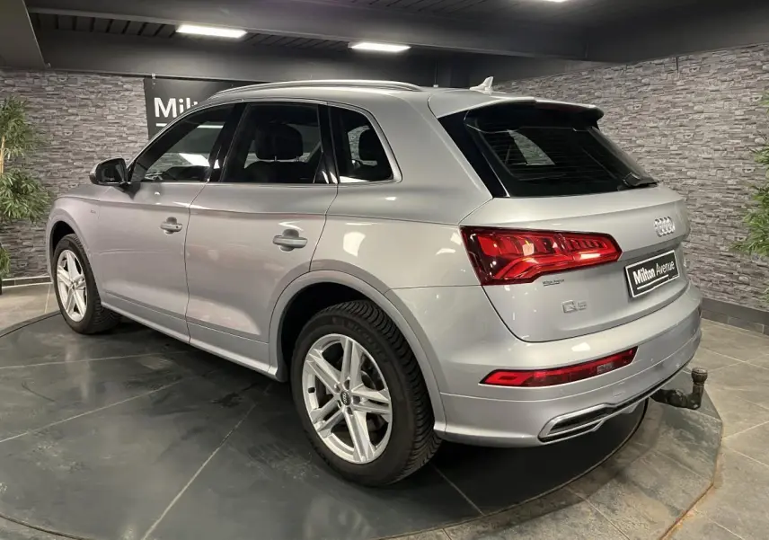 Audi Q5 gris en vue 3/4 arrière droit avec crochet d'attelage et jantes 5 branches doubles.