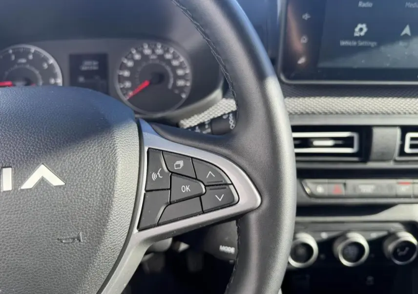 Gros plan sur le volant côté droit et tableau de bord avec écran tactile du Dacia Jogger gris Schiste 2025.