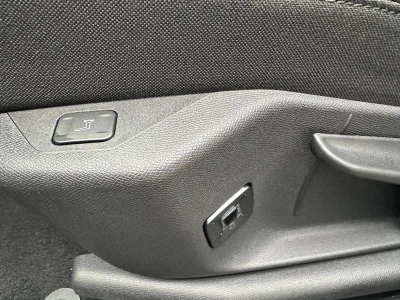 Gros plan sur les commandes de réglage de siège en tissu noir à l'intérieur du Peugeot 3008 Hybrid 2025.