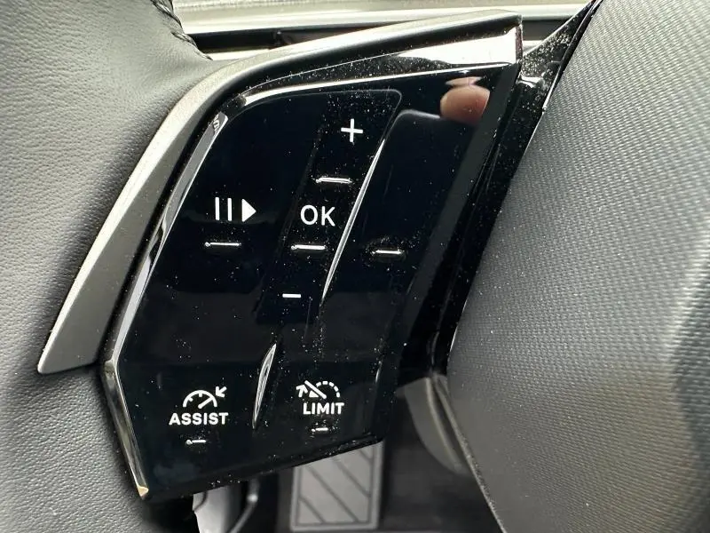 Gros plan sur les commandes au volant noir brillant du Peugeot 3008 Hybrid 2025, avec boutons multifonctions et réglages d'assistance.