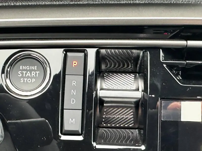 Gros plan sur la console centrale noire du Peugeot 3008 Hybrid avec bouton start/stop et sélecteur de boîte automatique.