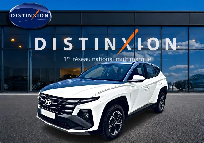 Hyundai Tucson blanc en 3/4 avant droit, avec calandre noire et jantes alliage 17 pouces visibles.