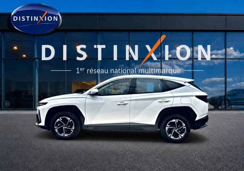Hyundai Tucson blanc en profil droit devant une vitrine avec logo Distinxion, jantes alliage 17 pouces visibles.