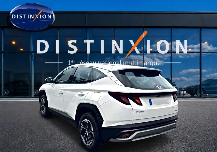 Vue 3/4 arrière droite d'un Hyundai Tucson blanc 2026 hybride avec jantes alliage et feux arrière LED distinctifs.